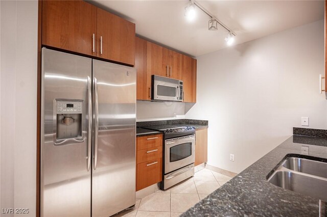 kitchen featuring rail lighting, sink, light tile patterned floors, and appliances with stainless steel finishes