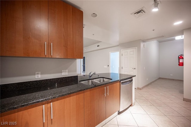 kitchen featuring dishwasher, light tile patterned floors, dark stone counters, and sink