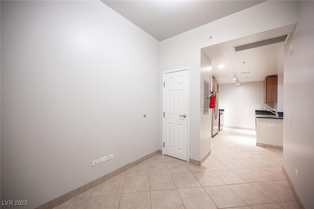 hallway featuring track lighting and light tile patterned flooring