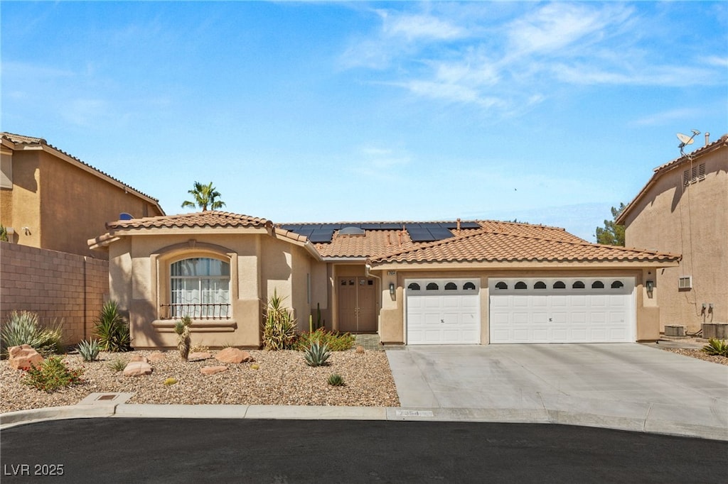 mediterranean / spanish-style home featuring solar panels, a garage, and central AC