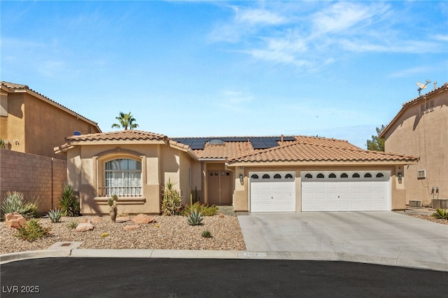 mediterranean / spanish-style home featuring solar panels, a garage, and central AC