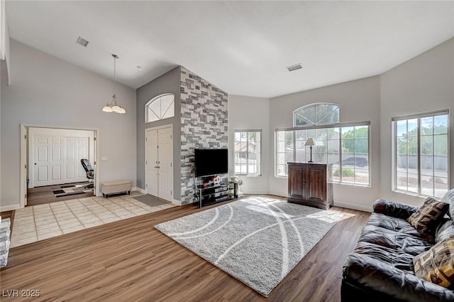 living room featuring light wood-type flooring, high vaulted ceiling, and an inviting chandelier