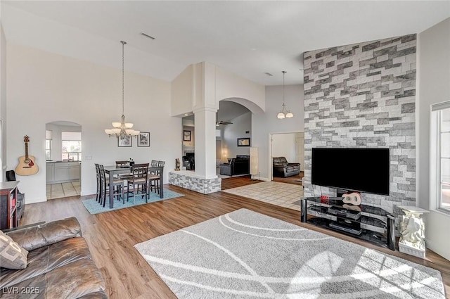 living room with hardwood / wood-style flooring, ceiling fan with notable chandelier, and high vaulted ceiling