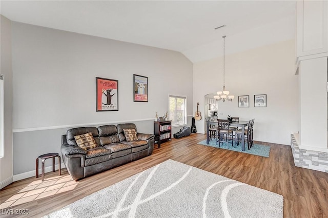 living room with hardwood / wood-style floors, a chandelier, and vaulted ceiling