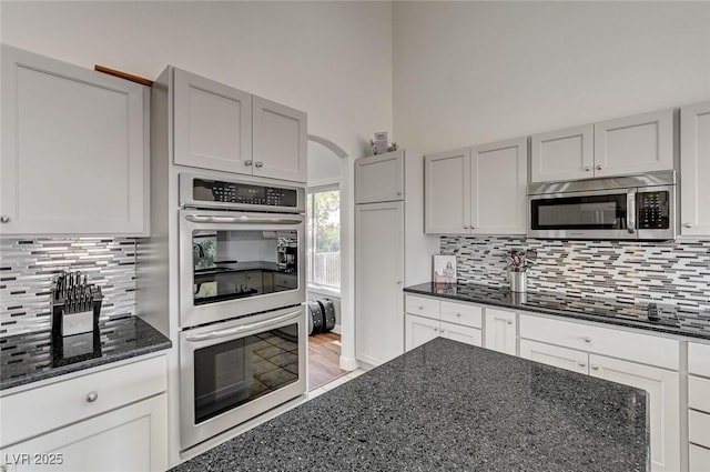 kitchen with tasteful backsplash, dark stone countertops, and stainless steel appliances