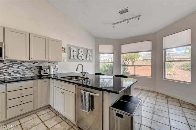 kitchen with backsplash, track lighting, sink, kitchen peninsula, and stainless steel appliances