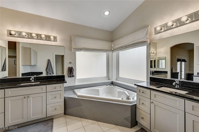 bathroom featuring tiled tub, tile patterned flooring, vanity, and vaulted ceiling