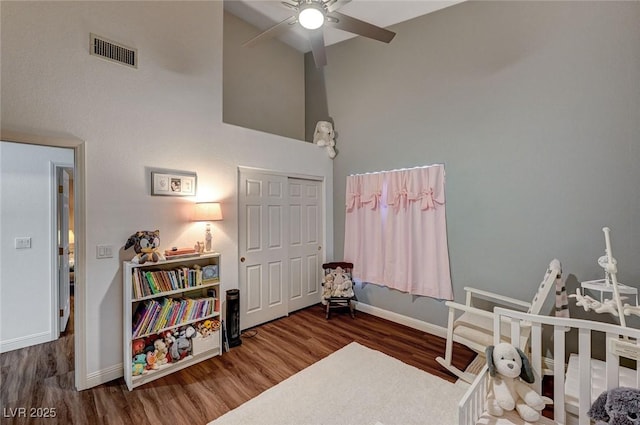 bedroom with ceiling fan, dark wood-type flooring, a high ceiling, and a closet