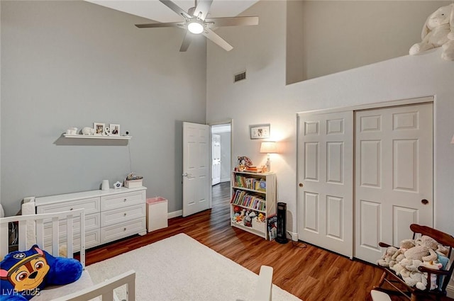 bedroom with ceiling fan, dark hardwood / wood-style floors, a high ceiling, and a closet