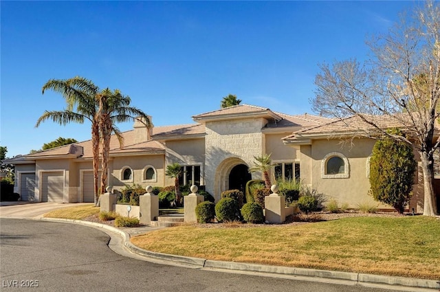 view of front of home with a front yard, driveway, an attached garage, stucco siding, and stone siding