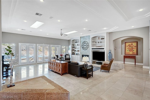 living room with french doors, built in shelves, ceiling fan, a fireplace, and plenty of natural light