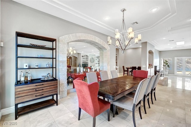 tiled dining area with a chandelier and a raised ceiling