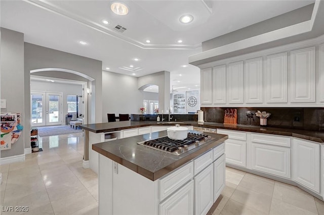 kitchen with french doors, stainless steel gas cooktop, sink, white cabinets, and a kitchen island