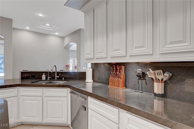 kitchen featuring white cabinets, sink, stainless steel dishwasher, light tile patterned floors, and tasteful backsplash