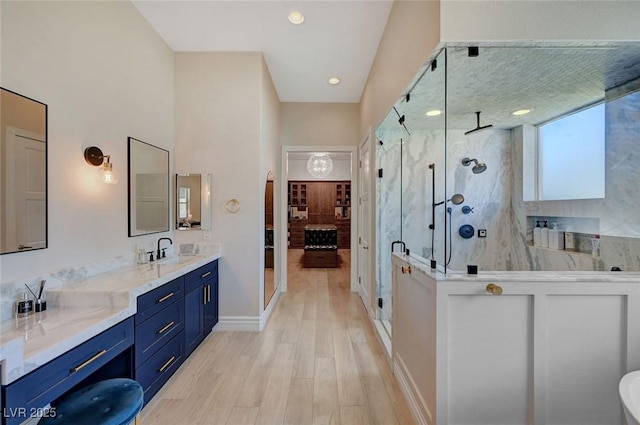 bathroom with hardwood / wood-style floors, vanity, and a shower with door