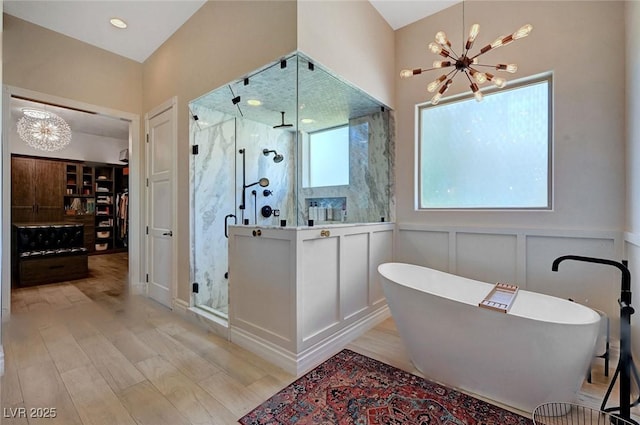 bathroom with separate shower and tub, hardwood / wood-style flooring, and an inviting chandelier