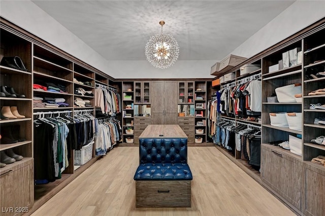 walk in closet featuring light hardwood / wood-style floors and an inviting chandelier