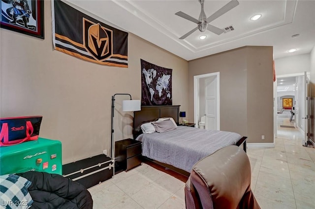 bedroom featuring a raised ceiling, ceiling fan, and light tile patterned flooring