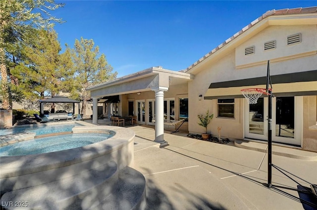 rear view of house with a gazebo, an in ground hot tub, french doors, and a patio