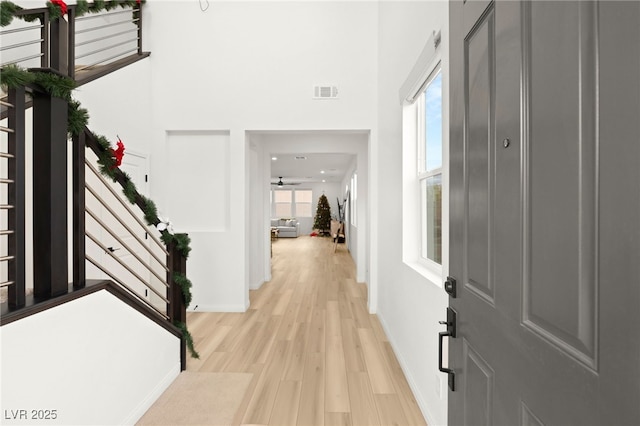 entryway with a wealth of natural light, ceiling fan, a high ceiling, and light wood-type flooring