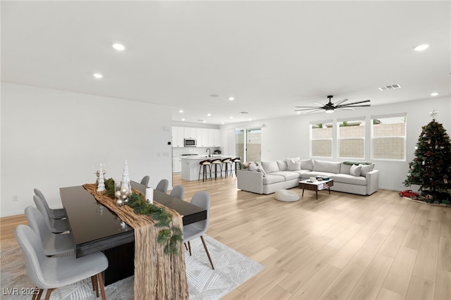 living room featuring ceiling fan, sink, and light hardwood / wood-style flooring