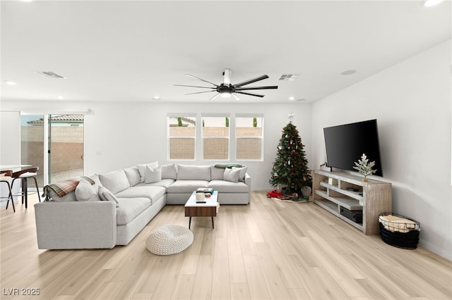 living room featuring plenty of natural light, ceiling fan, and light wood-type flooring