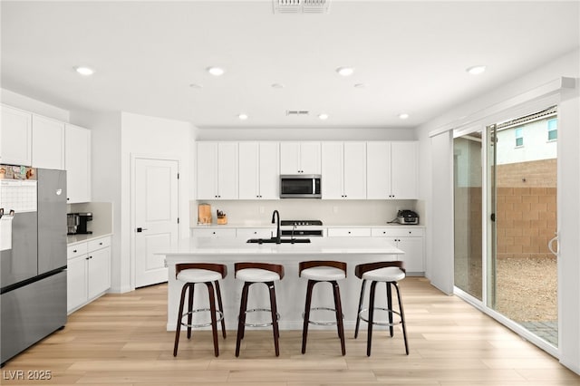 kitchen with white cabinets, an island with sink, and appliances with stainless steel finishes