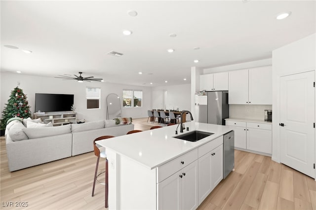 kitchen featuring ceiling fan, sink, a center island with sink, white cabinets, and appliances with stainless steel finishes