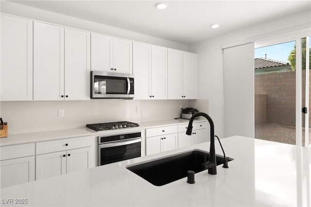 kitchen with appliances with stainless steel finishes, white cabinetry, and sink