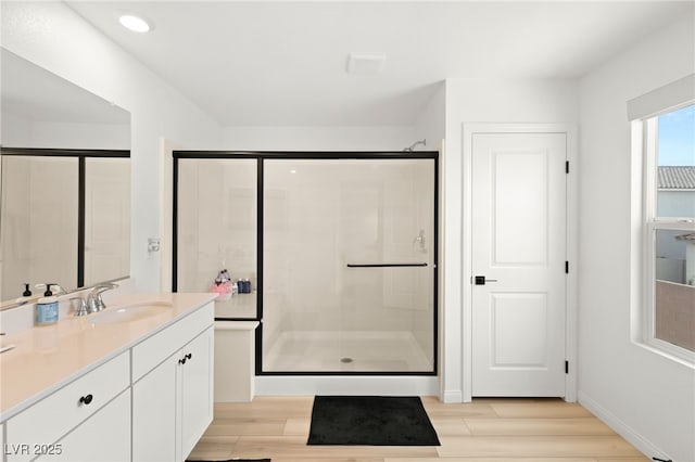 bathroom with wood-type flooring, vanity, and a shower with door