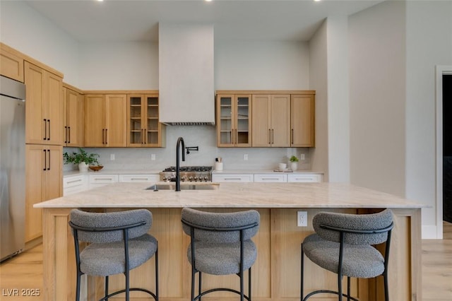 kitchen with light brown cabinets, a kitchen bar, and an island with sink