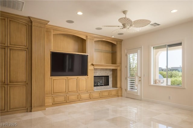 unfurnished living room featuring a premium fireplace and ceiling fan