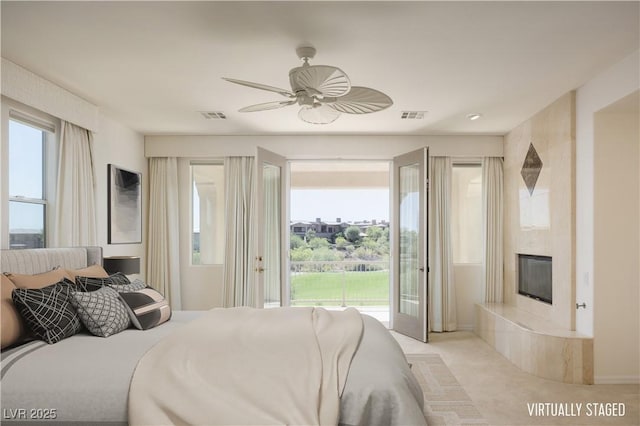 bedroom with access to outside, ceiling fan, a fireplace, and light carpet