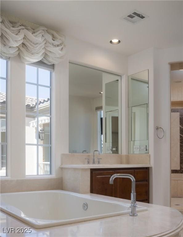 bathroom featuring vanity and a relaxing tiled tub