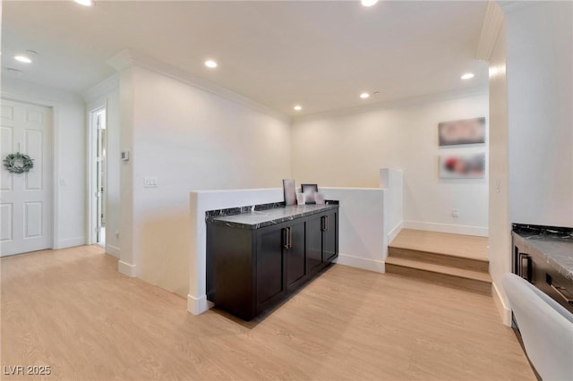 bar featuring dark stone countertops, crown molding, and light hardwood / wood-style flooring