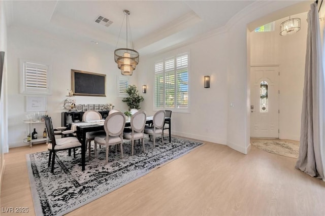 dining room featuring a tray ceiling, light hardwood / wood-style flooring, and ornamental molding