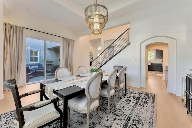 dining area with a chandelier, light wood-type flooring, and crown molding