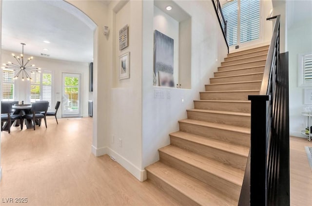 stairs featuring hardwood / wood-style flooring and a chandelier