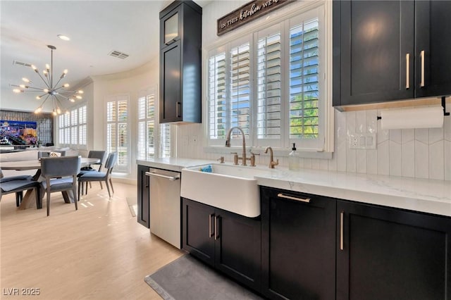 kitchen featuring pendant lighting, dishwasher, sink, light hardwood / wood-style flooring, and light stone counters