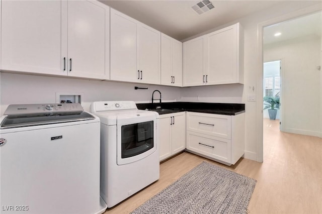 laundry room featuring cabinets, sink, light hardwood / wood-style flooring, and washing machine and clothes dryer