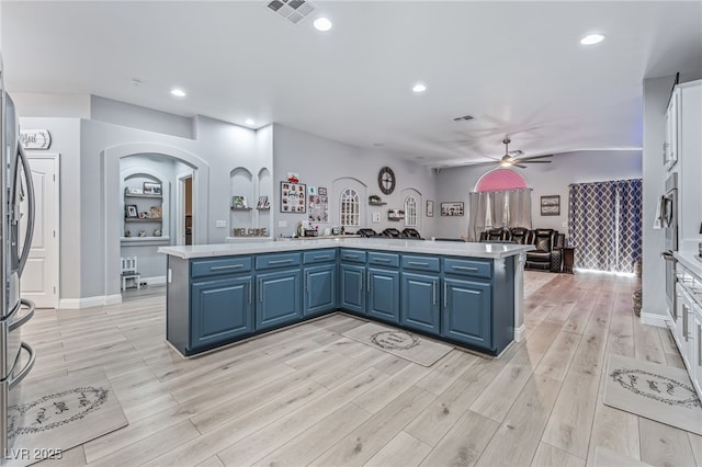 kitchen featuring blue cabinetry, kitchen peninsula, ceiling fan, and oven