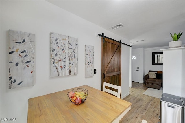 dining room with light hardwood / wood-style floors and a barn door