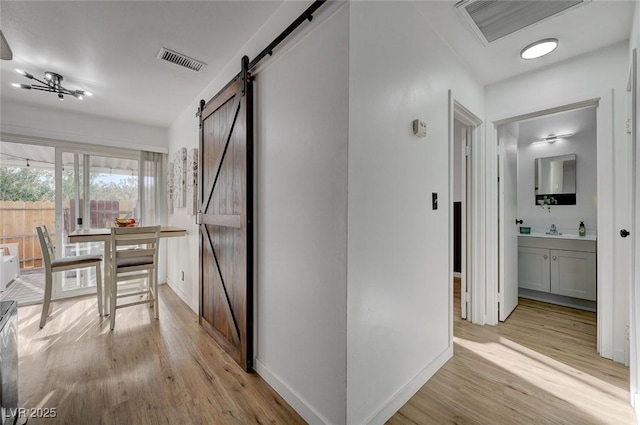 corridor featuring a barn door and light hardwood / wood-style flooring