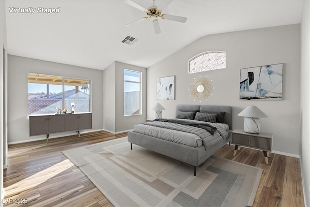 bedroom with ceiling fan, vaulted ceiling, wood-type flooring, and multiple windows