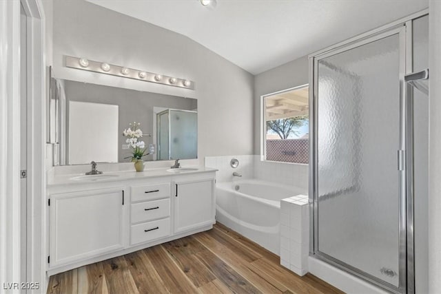 bathroom featuring hardwood / wood-style floors, vanity, plus walk in shower, and vaulted ceiling