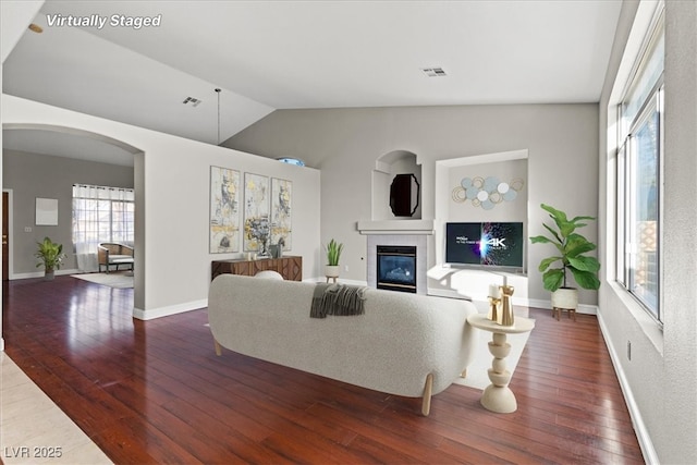 living room with dark hardwood / wood-style flooring, lofted ceiling, and a tile fireplace