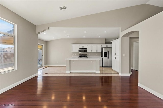 kitchen with a center island with sink, white cabinets, lofted ceiling, and appliances with stainless steel finishes