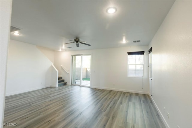 empty room with hardwood / wood-style flooring, ceiling fan, and plenty of natural light