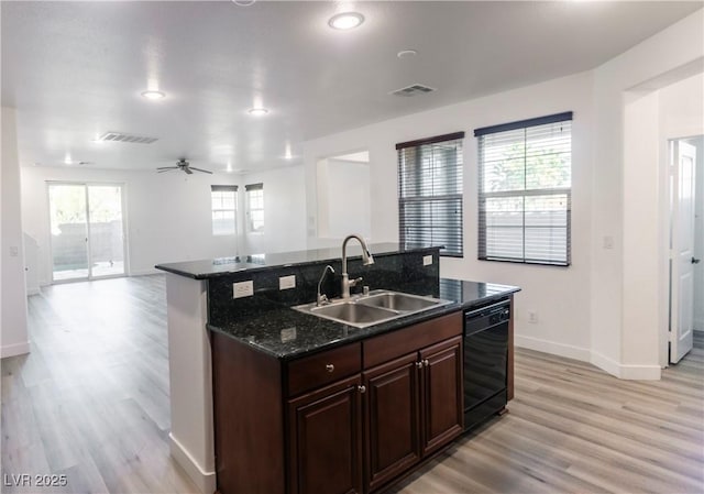 kitchen featuring ceiling fan, sink, light hardwood / wood-style flooring, dark stone countertops, and black dishwasher