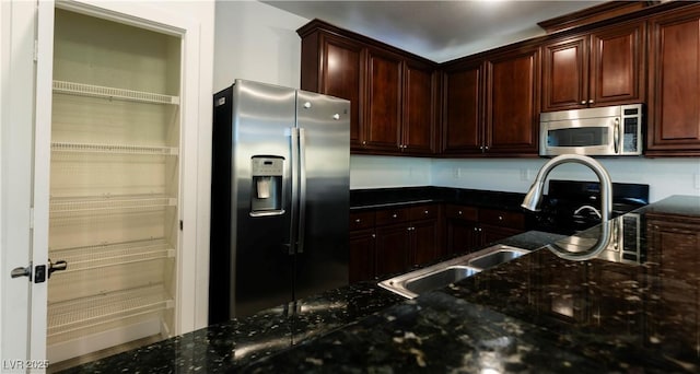 kitchen featuring sink, appliances with stainless steel finishes, and dark stone counters